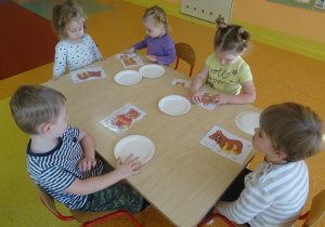 Piątka dzieci w pojedynkę składa obrazek misia z części.